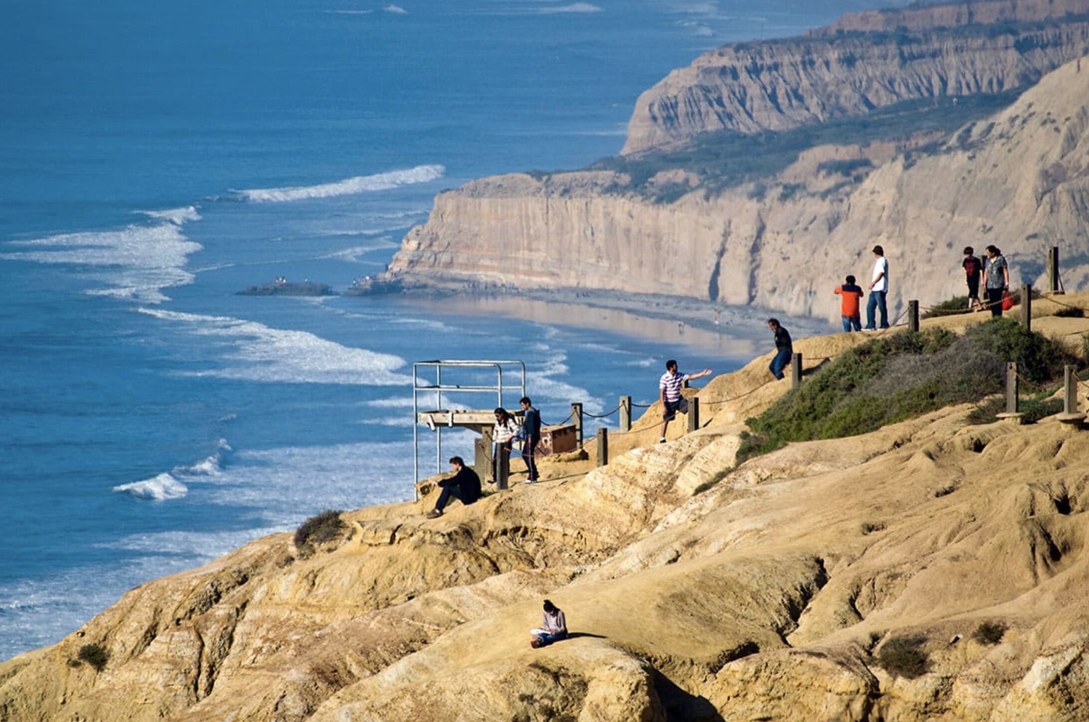 A coastal cliff with people enjoying the view.