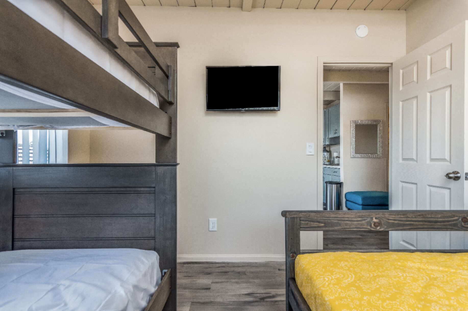 Een slaapkamer met stapelbedden, een televisie aan de muur en een deur naar een badkamer.