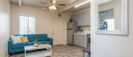 A living room with a teal sofa, a white coffee table, and a ceiling fan.
