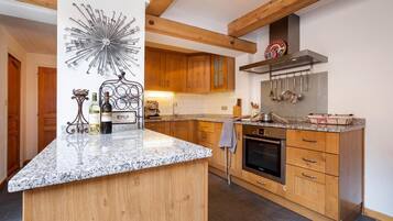 Une cuisine moderne avec des meubles en bois, un plan de travail en granit et un four encastré.