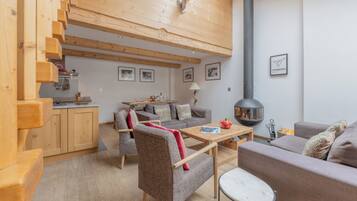 Un intérieur moderne avec un escalier en bois, un coin repas, un canapé et une cheminée.