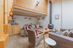 Ein modernes Interieur mit einer Holztreppe, einem Essbereich, einer Couch und einem Kamin.