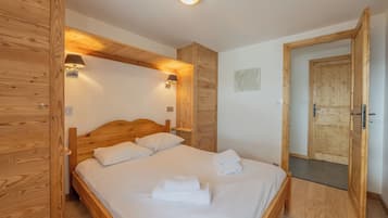 Une pièce avec un cadre en bois, comprenant un lit, deux lampes fixées au mur et une porte.