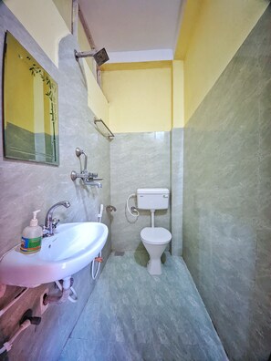 Un baño pequeño con lavamanos blanco, espejo, inodoro y ducha.