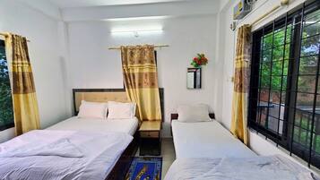 Habitación de hotel con dos camas, un espejo, una ventana que da a zonas verdes y un equipo de aire acondicionado.