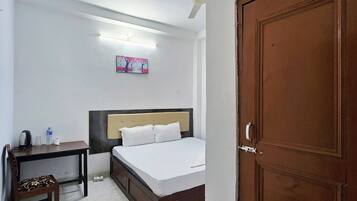 A bedroom with a bed, a desk, a chair, a wardrobe, and a ceiling fan.