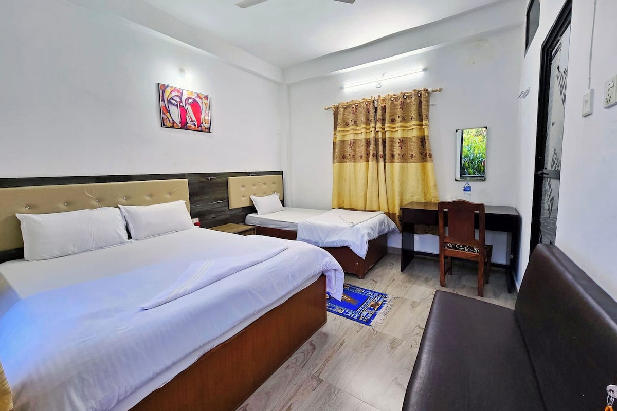 A hotel room with two beds, a desk, a chair, a ceiling fan, and a window with curtains.