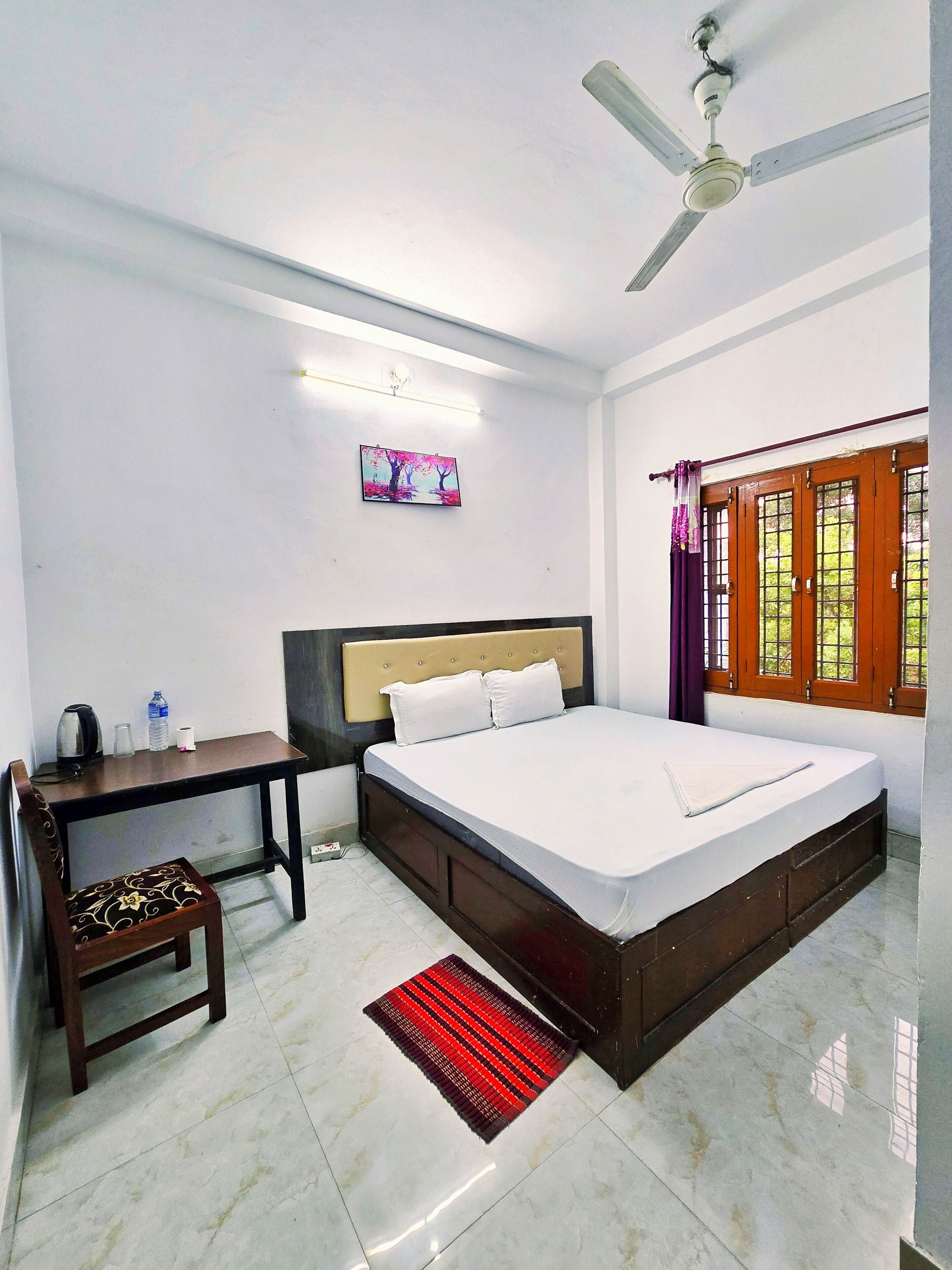 A bedroom with a bed, desk, chair, and a ceiling fan.