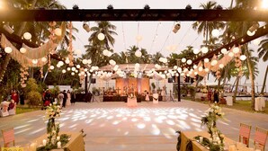 Un lieu de réception en plein air pour les mariages, doté d’une scène, de palmiers et de guirlandes lumineuses.