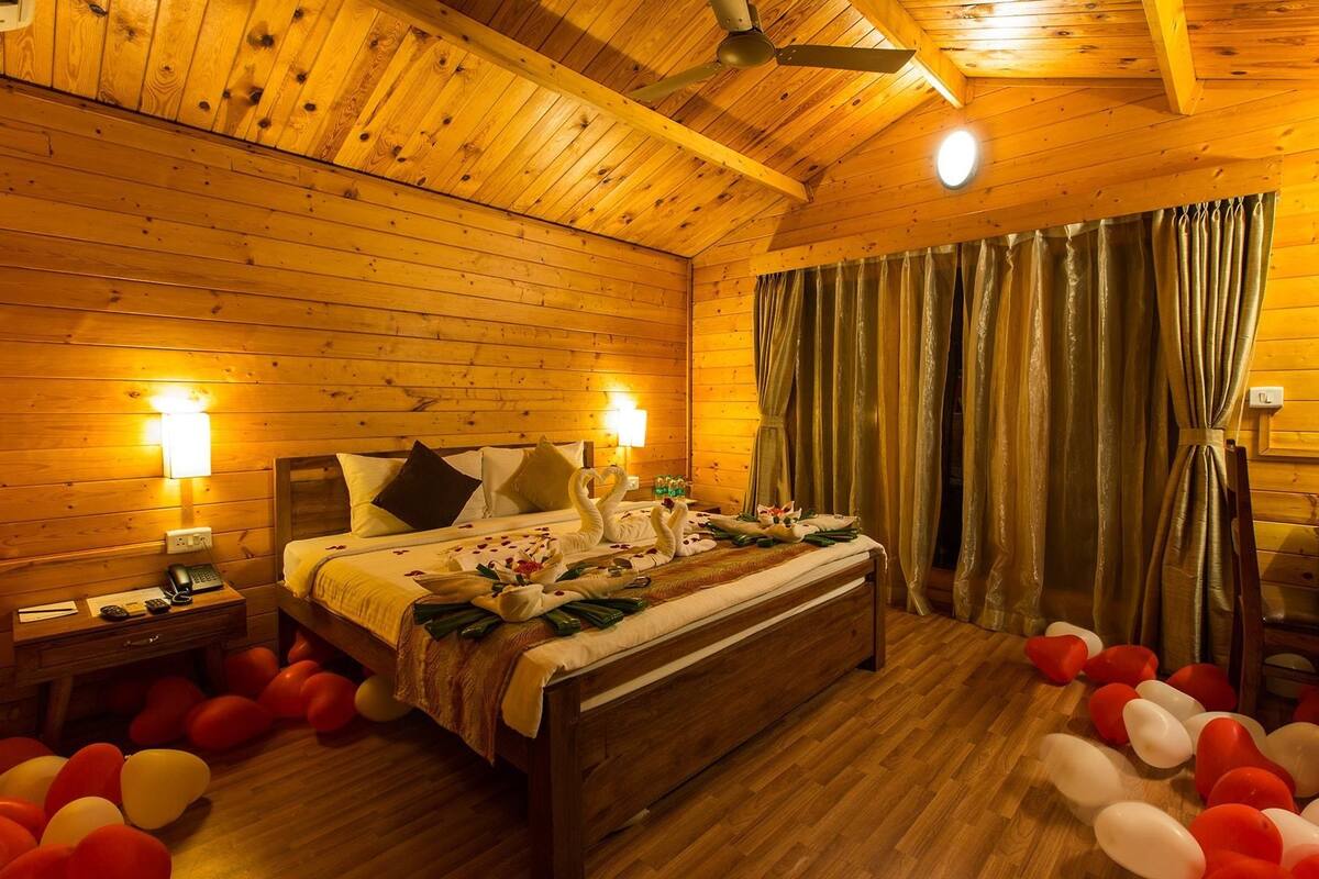 Um quarto acolhedor de madeira com uma cama, abajures e balões no chão.