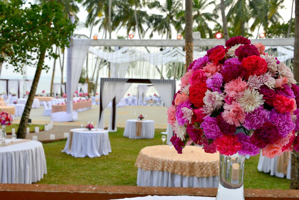 Un lugar para bodas al aire libre con mesas redondas, toldos blancos y un gran arreglo floral.