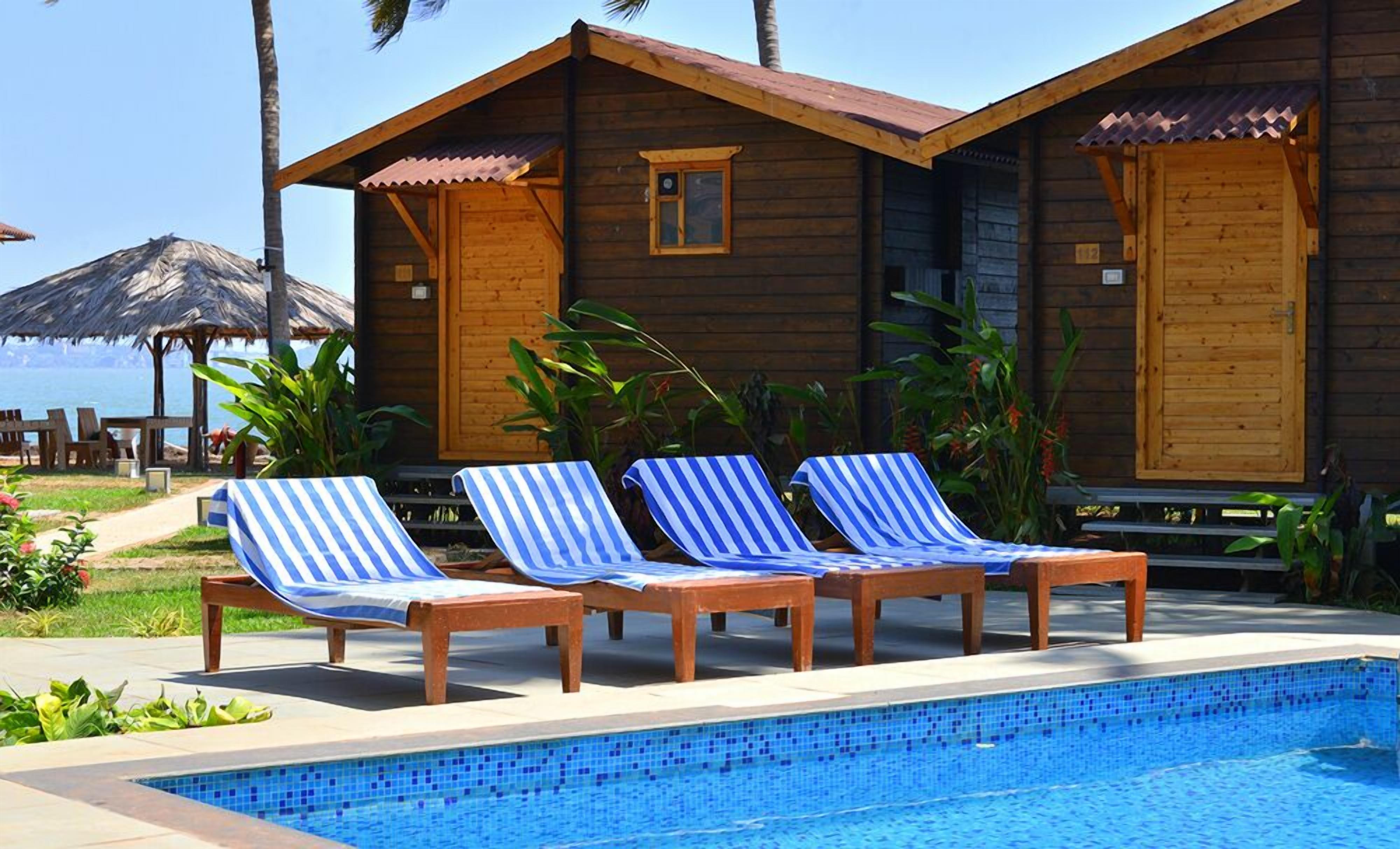 A wooden cabin with a pool and lounge chairs.