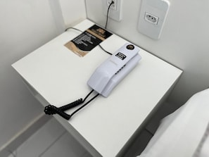 A white bedside table with a white power strip and a black charging cable. - Goiana Palace Hotel (Goiana)