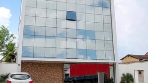 A modern building with a glass facade, a parking area, and a red truck parked outside. - Goiana Palace Hotel (Goiana)