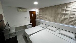 A hotel room with two beds, a small desk, a mirror, and a window with blinds. - Goiana Palace Hotel (Goiana)