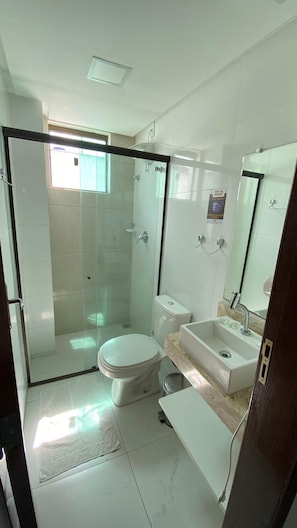 A modern bathroom with a glass-enclosed shower, a toilet, a sink, and a mirror. - Goiana Palace Hotel (Goiana)