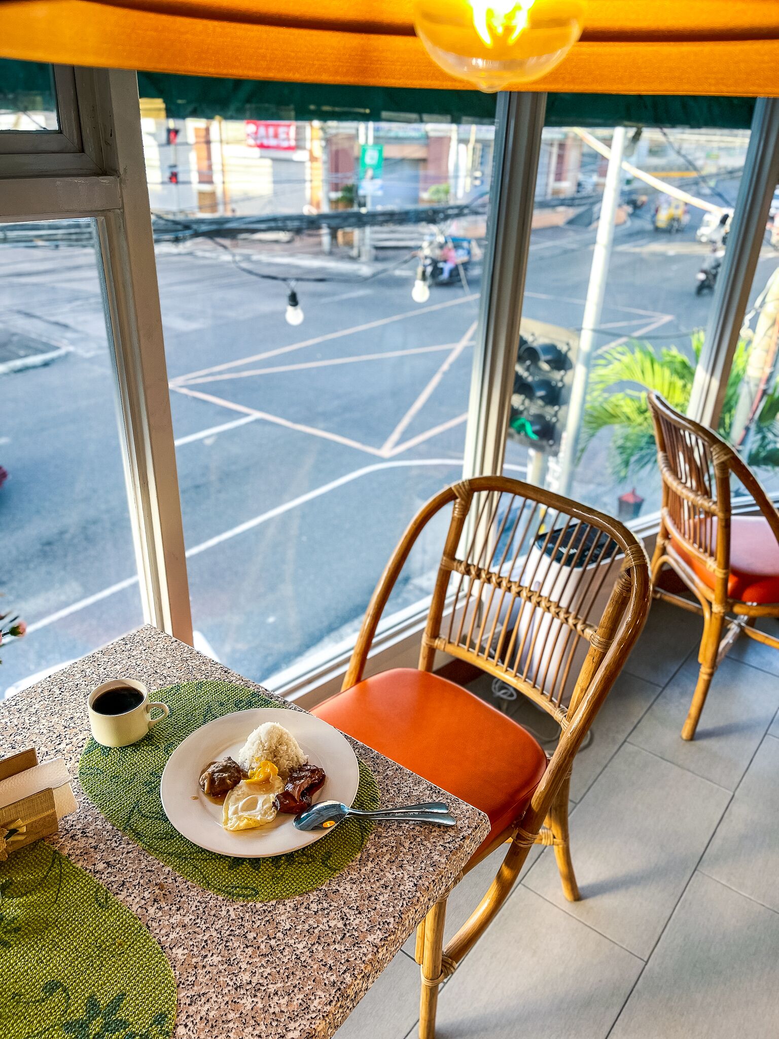 En spiseplads med et bord dækket til to personer, med mad og en kop kaffe.