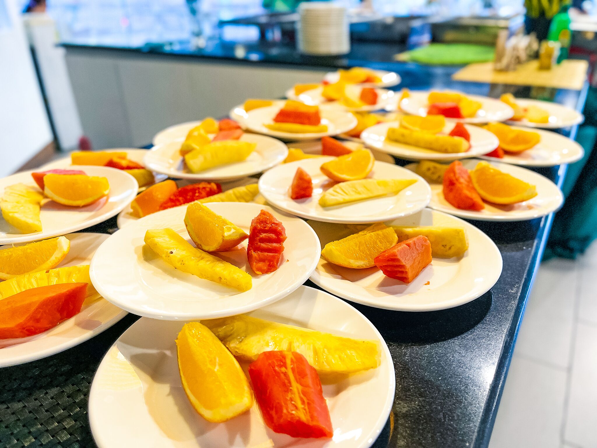 A buffet table with plates of sliced fruits.