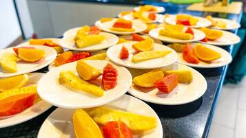 Une table de buffet avec des assiettes remplies de fruits coupés en tranches.