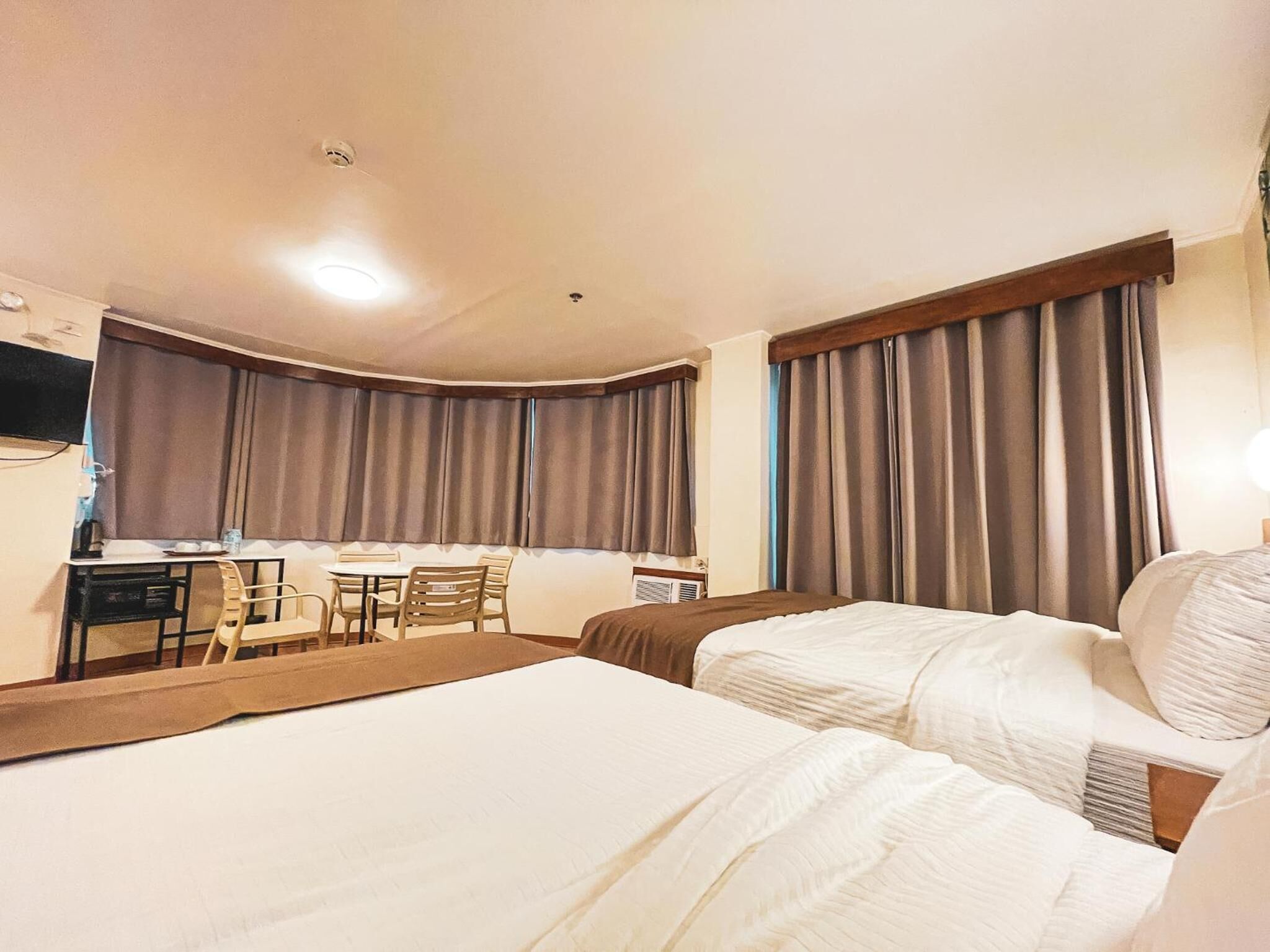 Habitación de hotel con dos camas, un escritorio y una silla.
