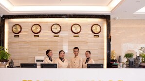 A hotel reception desk with clocks displaying different time zones and a sign reading "HOTEL TUGOS". - Hotel Tugos (Baguio)