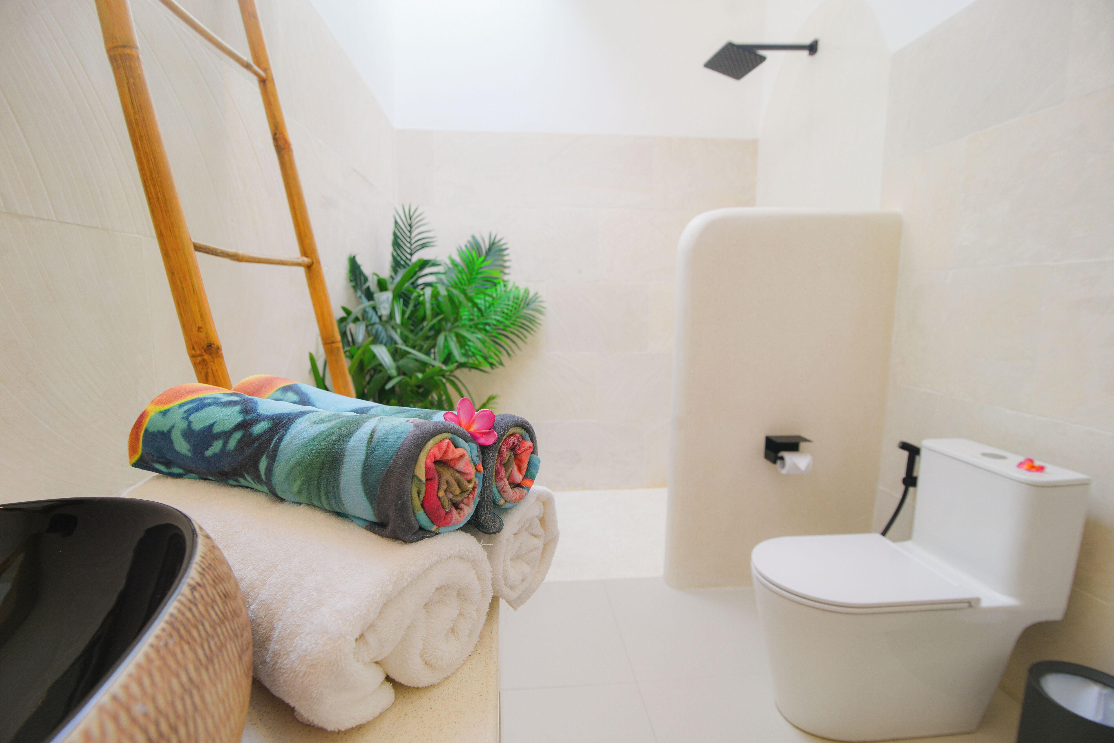Un baño con inodoro, lavamanos, toallero y toallas, y una planta pequeña.