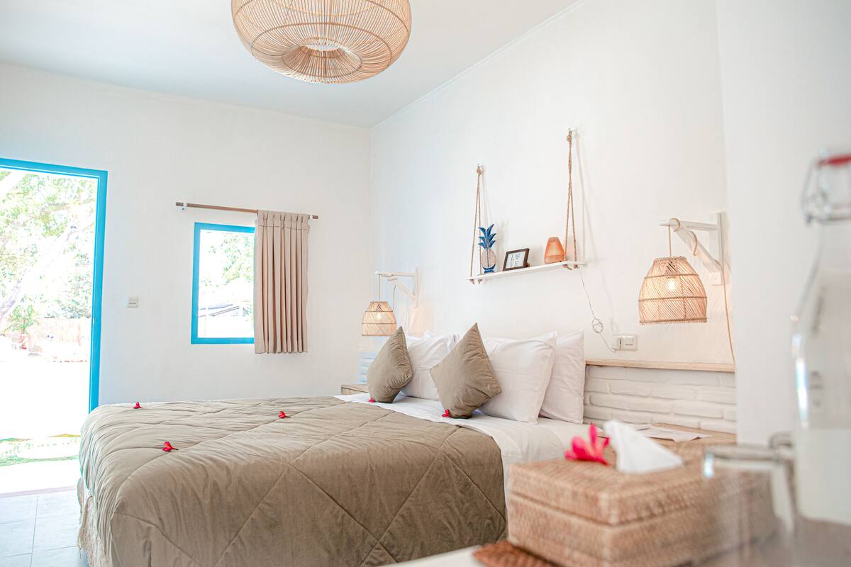 Une chambre à coucher comprenant un lit, une fenêtre, une porte et une étagère fixée au mur, ornée d’objets décoratifs.