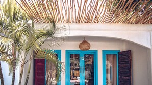 A building with a number 13 door, blue shutters, and a woven ceiling.