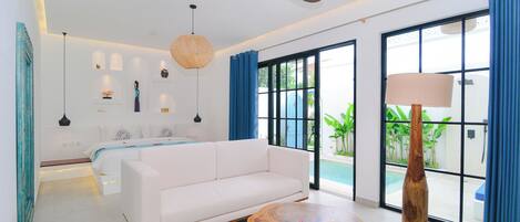 A modern bedroom with a white sofa, a wooden coffee table, and a ceiling fan.