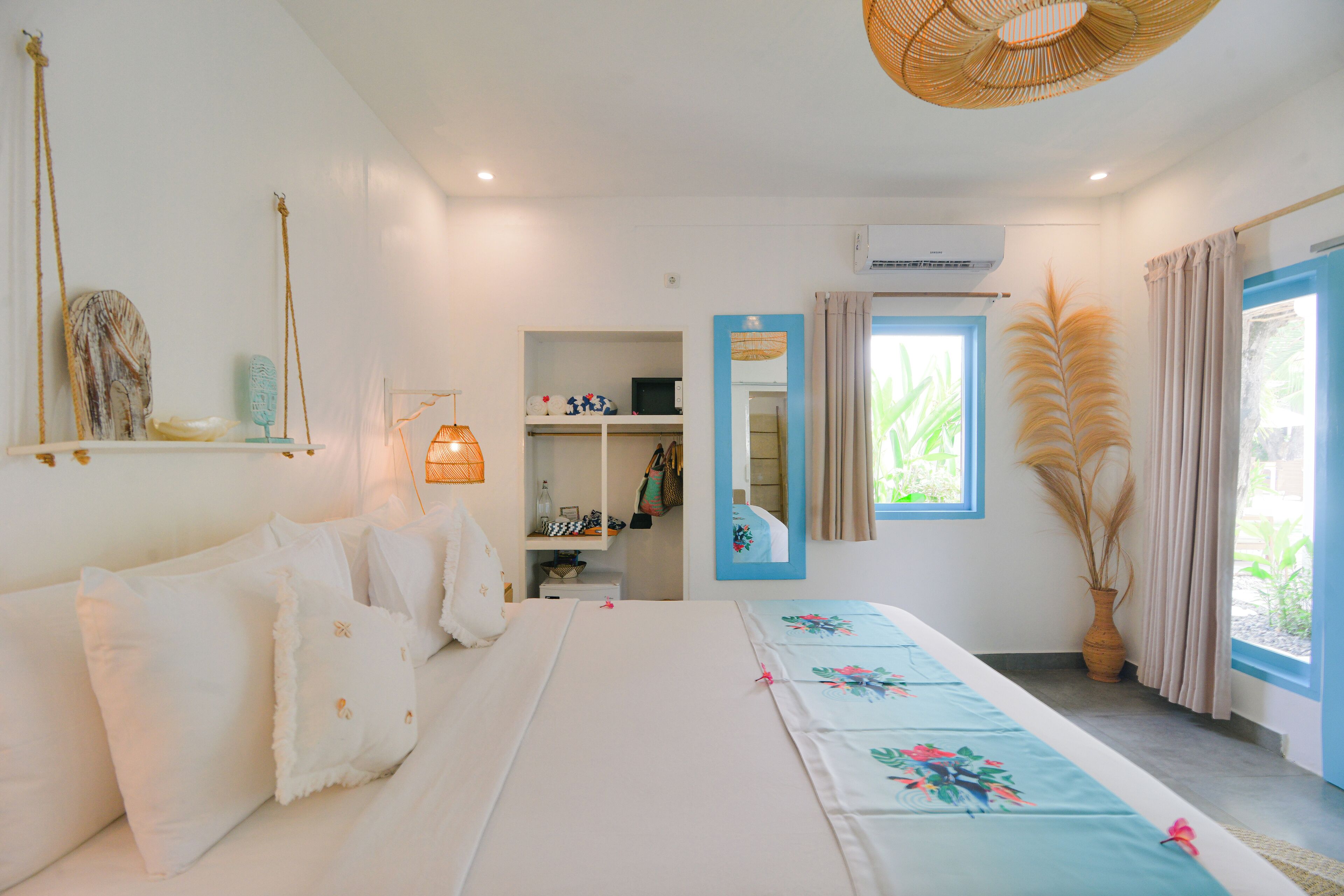 Un dormitorio con cama, armario, espejo y ventana con cortinas.