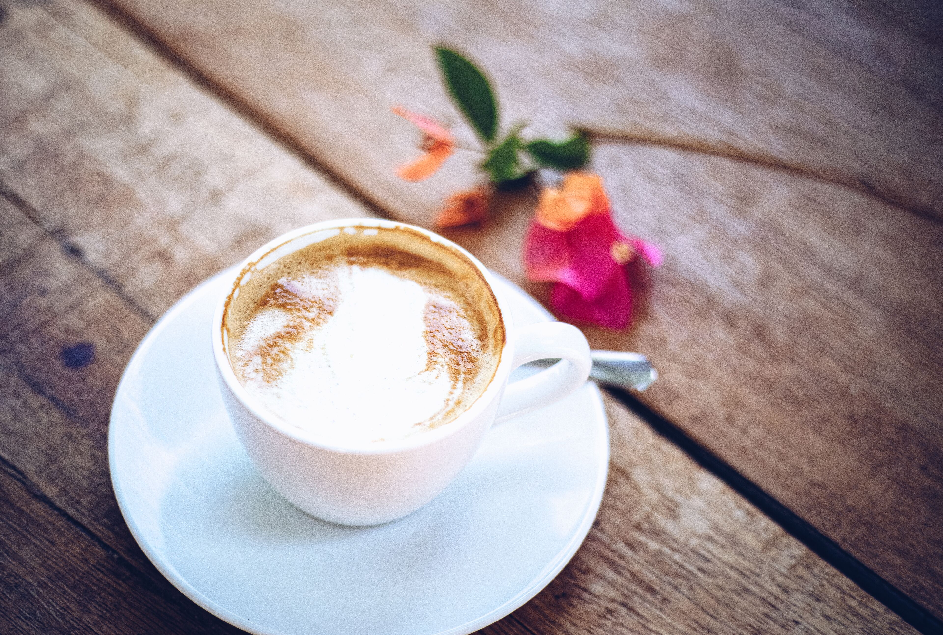 Une tasse de café sur une soucoupe blanche, posée sur une table en bois.