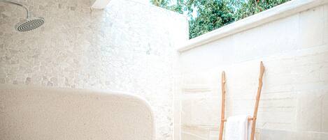 A bathroom with a stone wall, a shower, and a wooden ladder.