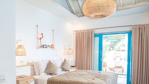 A bedroom with a bed, bedside tables, a hanging light fixture, and a view of the outdoors through a door.