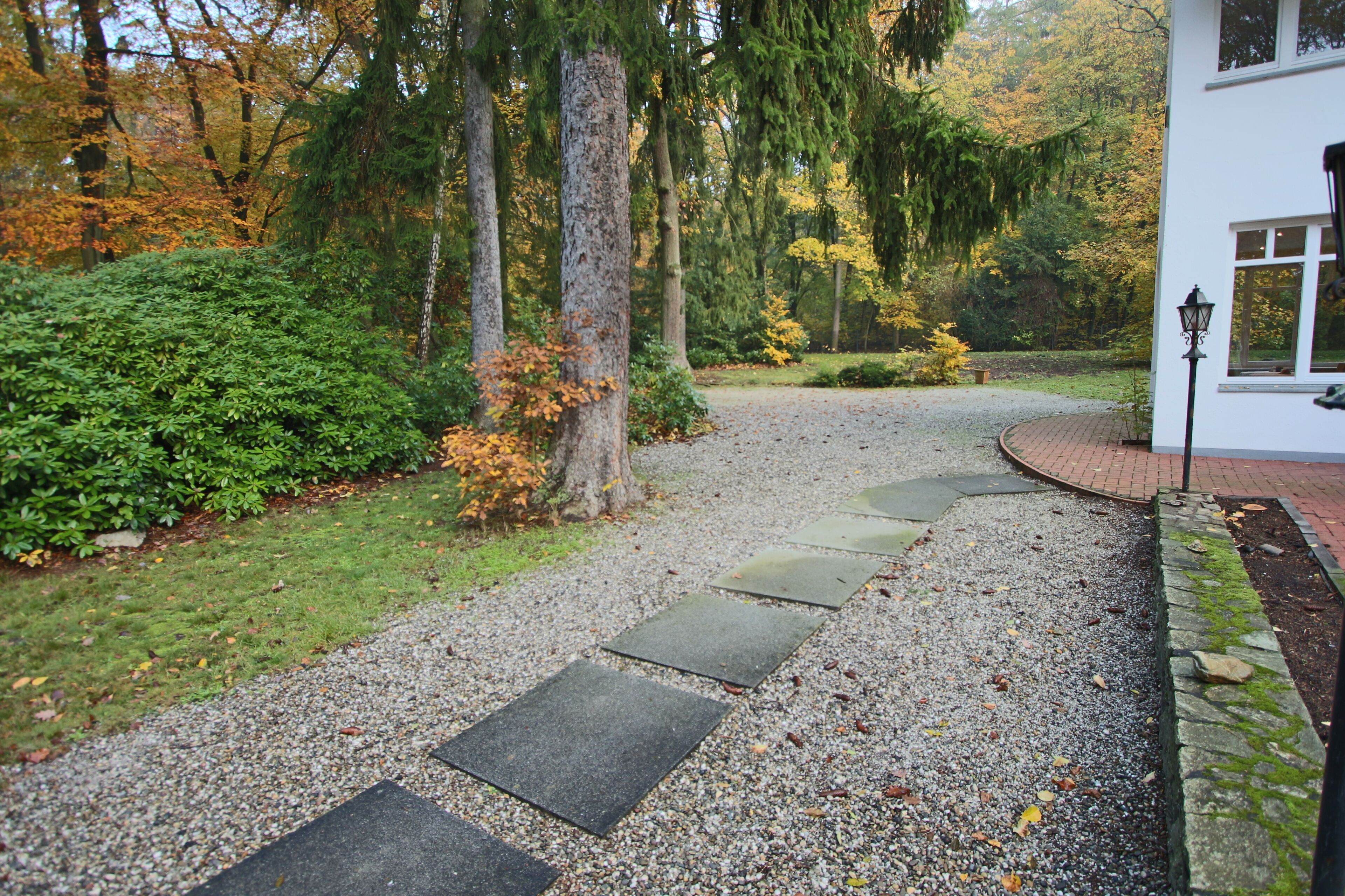 A gravel pathway leading to a white building with a window and a lamp post.