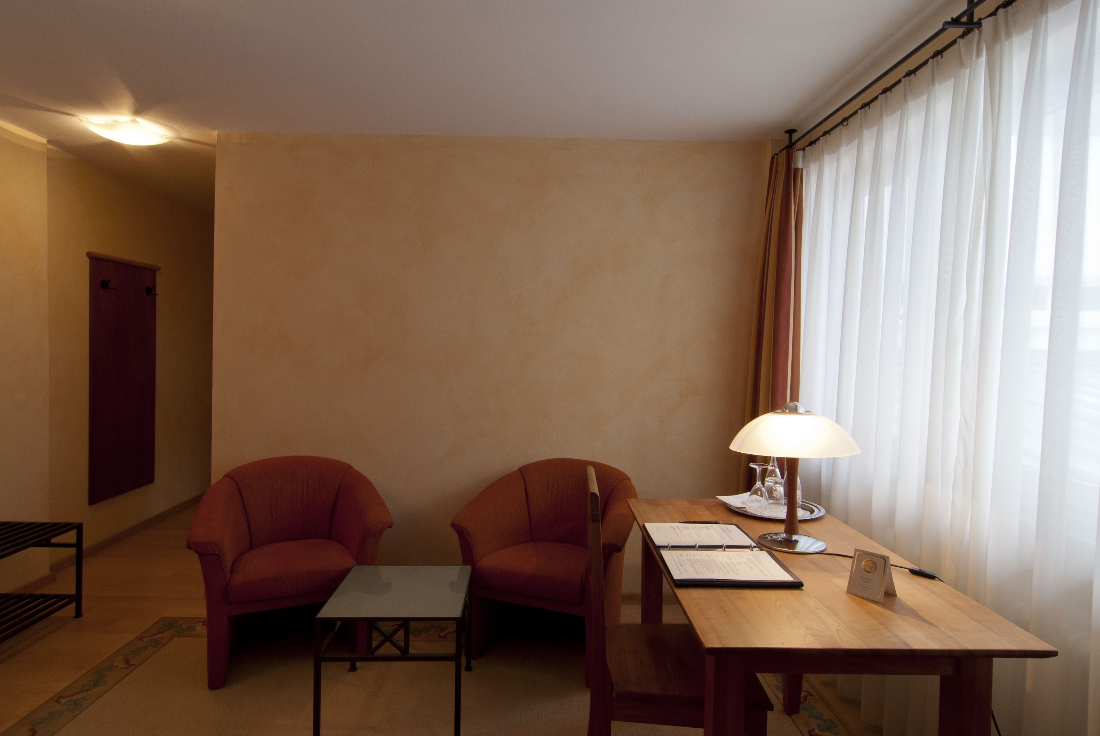 Una habitación con dos sillones, una pequeña mesa, una lámpara y una puerta.