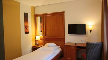 Een hotelkamer met een bed, een bureau, een televisie en een spiegel aan de muur.