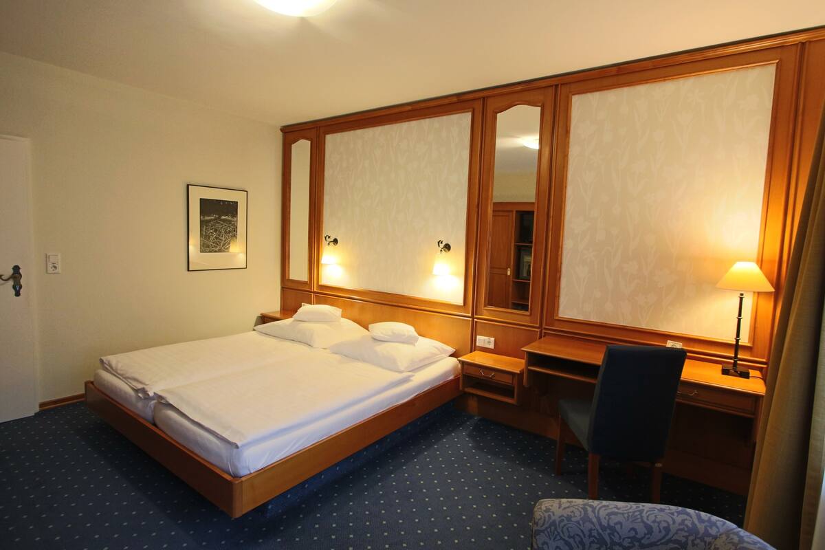 Une chambre d’hôtel avec un grand lit, un bureau et une chaise.