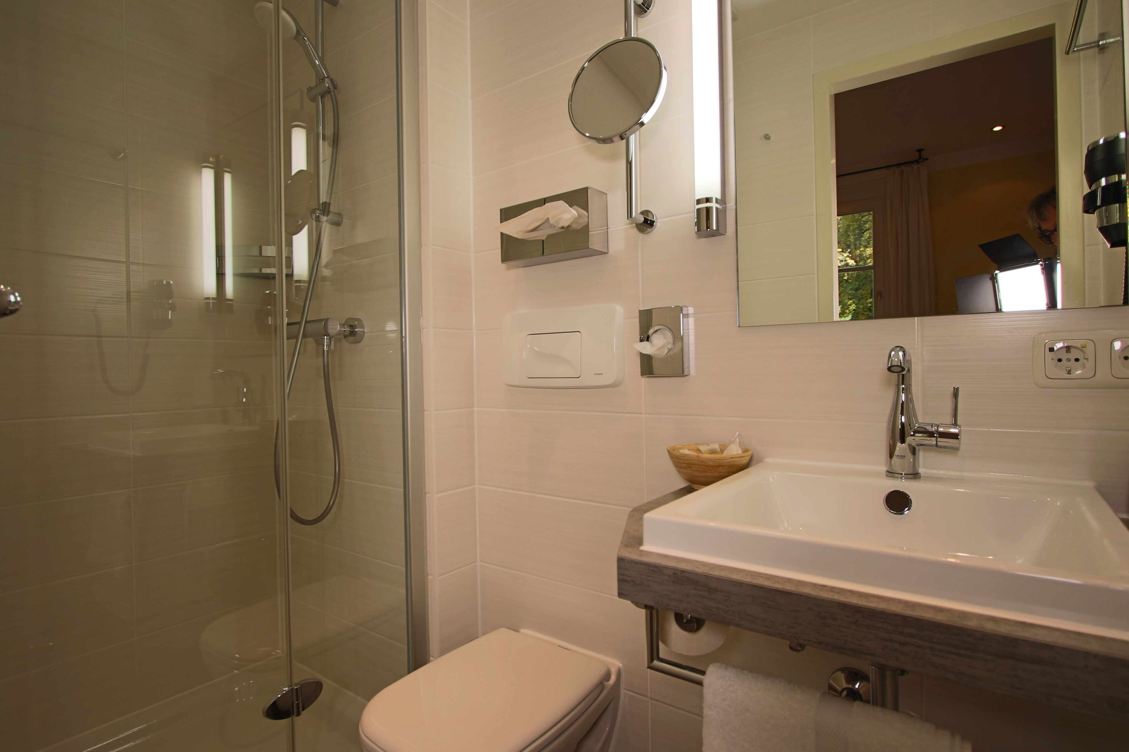 A modern bathroom with a glass-enclosed shower, a white toilet, a sink with a mirror, and a towel rack.