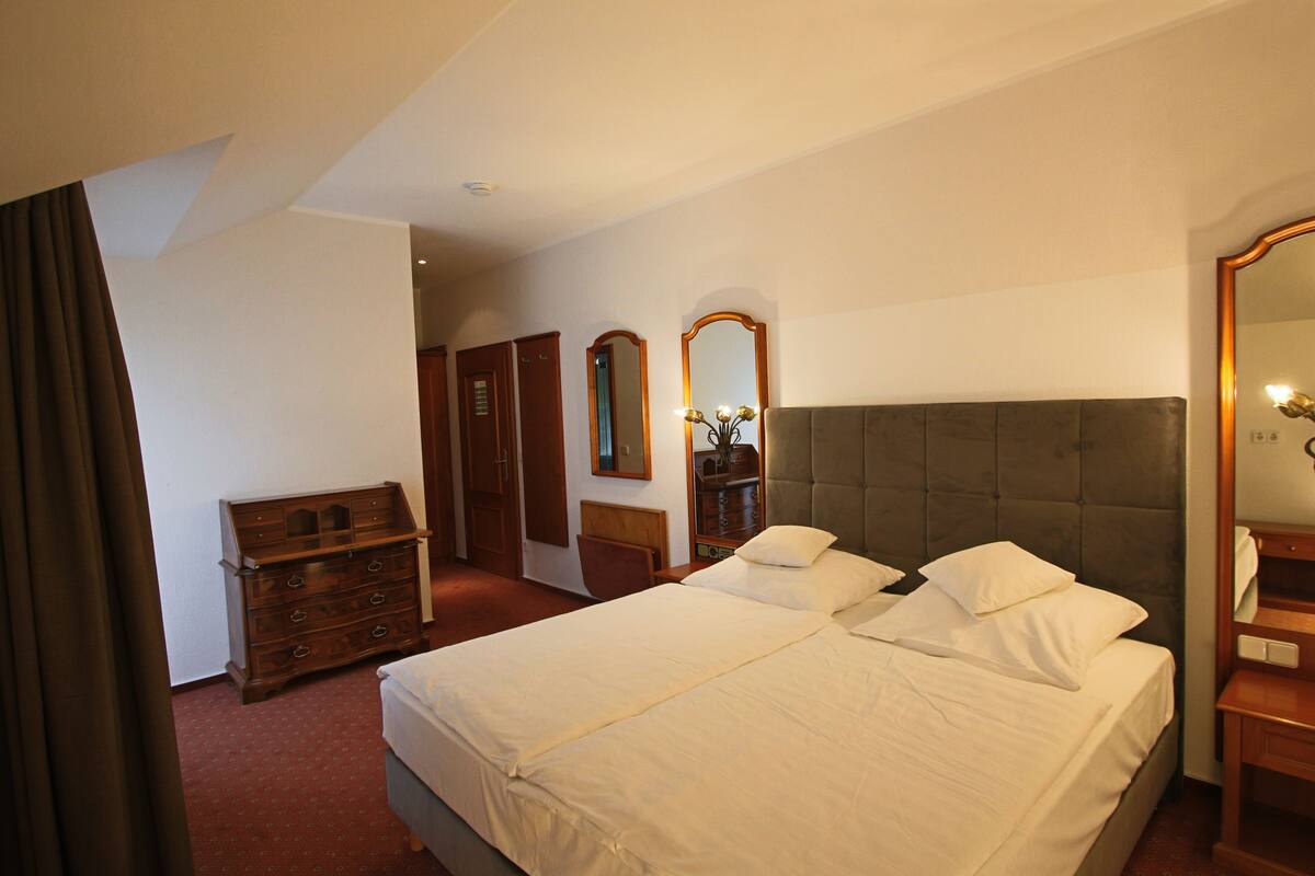 Une chambre d’hôtel avec un grand lit, une commode, un miroir et une armoire.