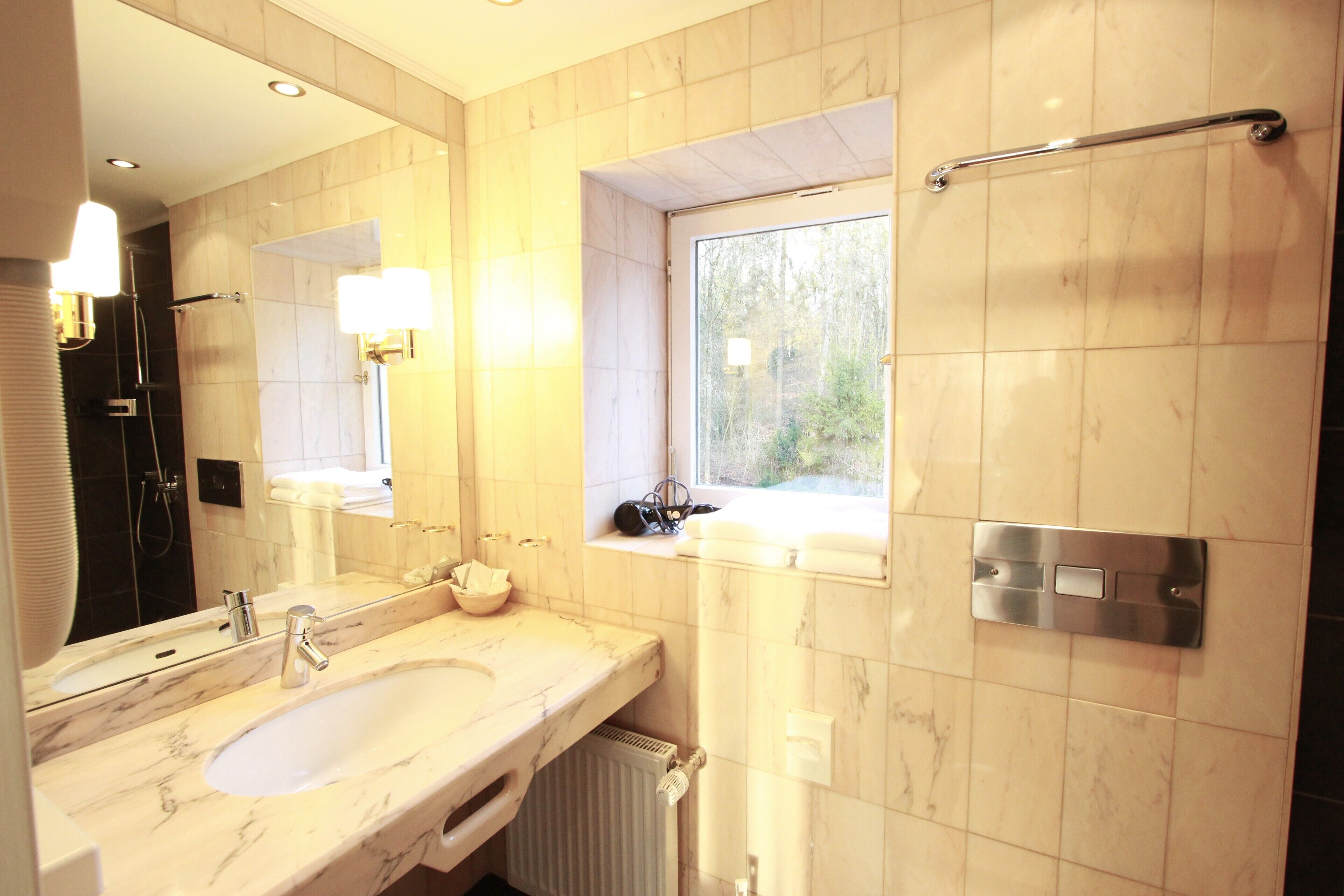 Un baño moderno con un lavamanos grande, un espejo, una ventana y una ducha.