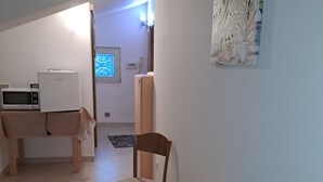 A kitchen with a microwave, a refrigerator, and a wooden table.
