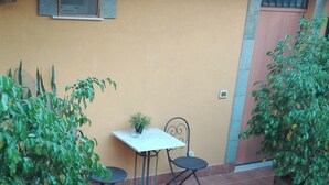 A patio area with a table and two chairs, surrounded by potted plants.
