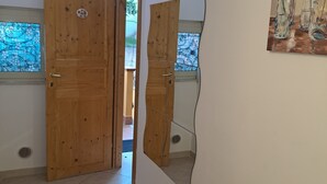 A hallway with wooden doors, a patterned rug, a wall-mounted mirror, and a painting.