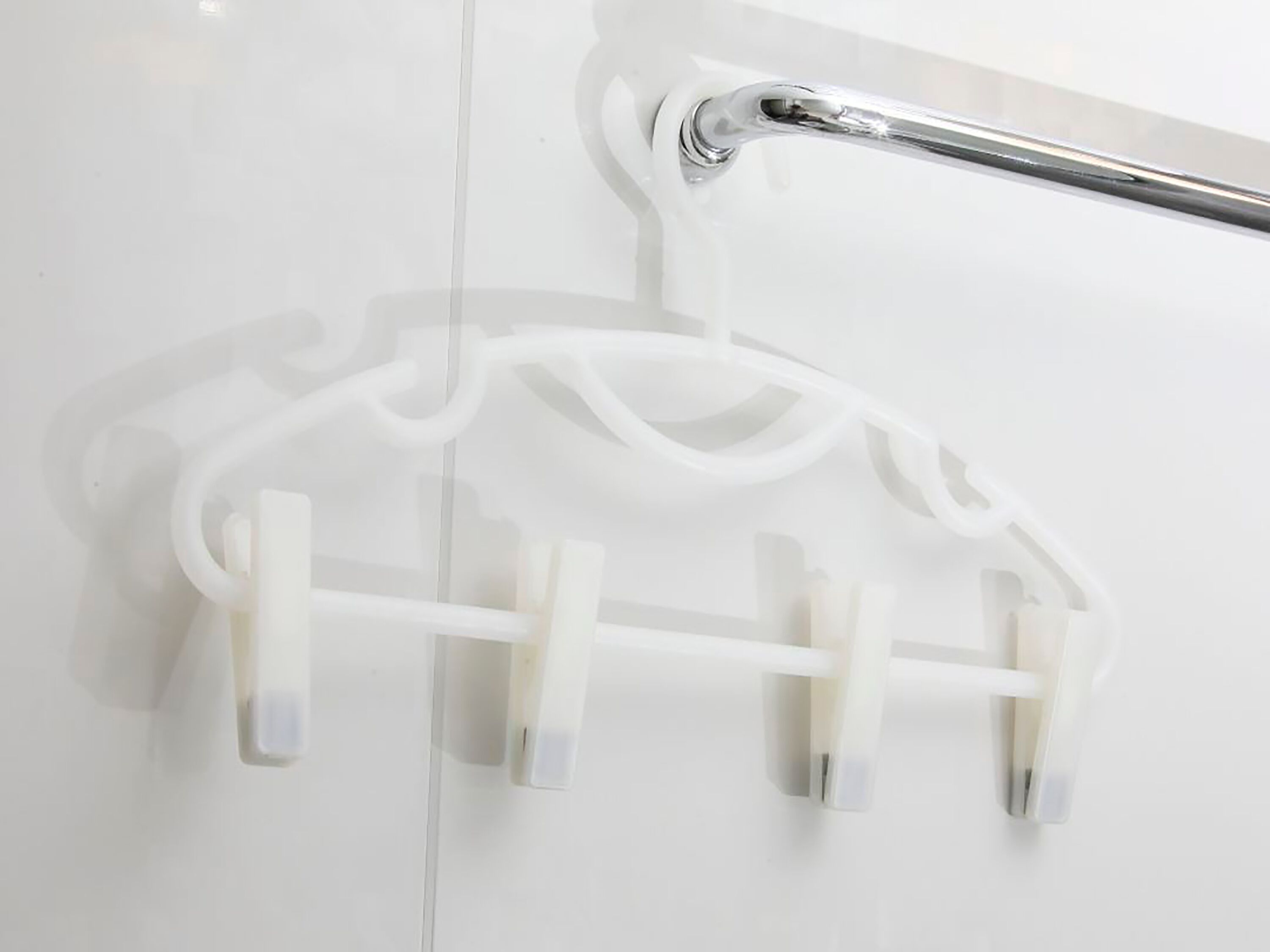 A bathroom with a white bathtub, a chrome faucet, and a white towel rack with multiple hooks.