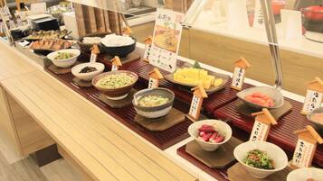 Un mostrador de buffet con diversos platos expuestos en cuencos y fuentes, cada uno con texto en japonés.