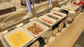 Ein Buffet mit verschiedenen Speisen in separaten Behältern, die jeweils mit Schildern beschriftet sind.