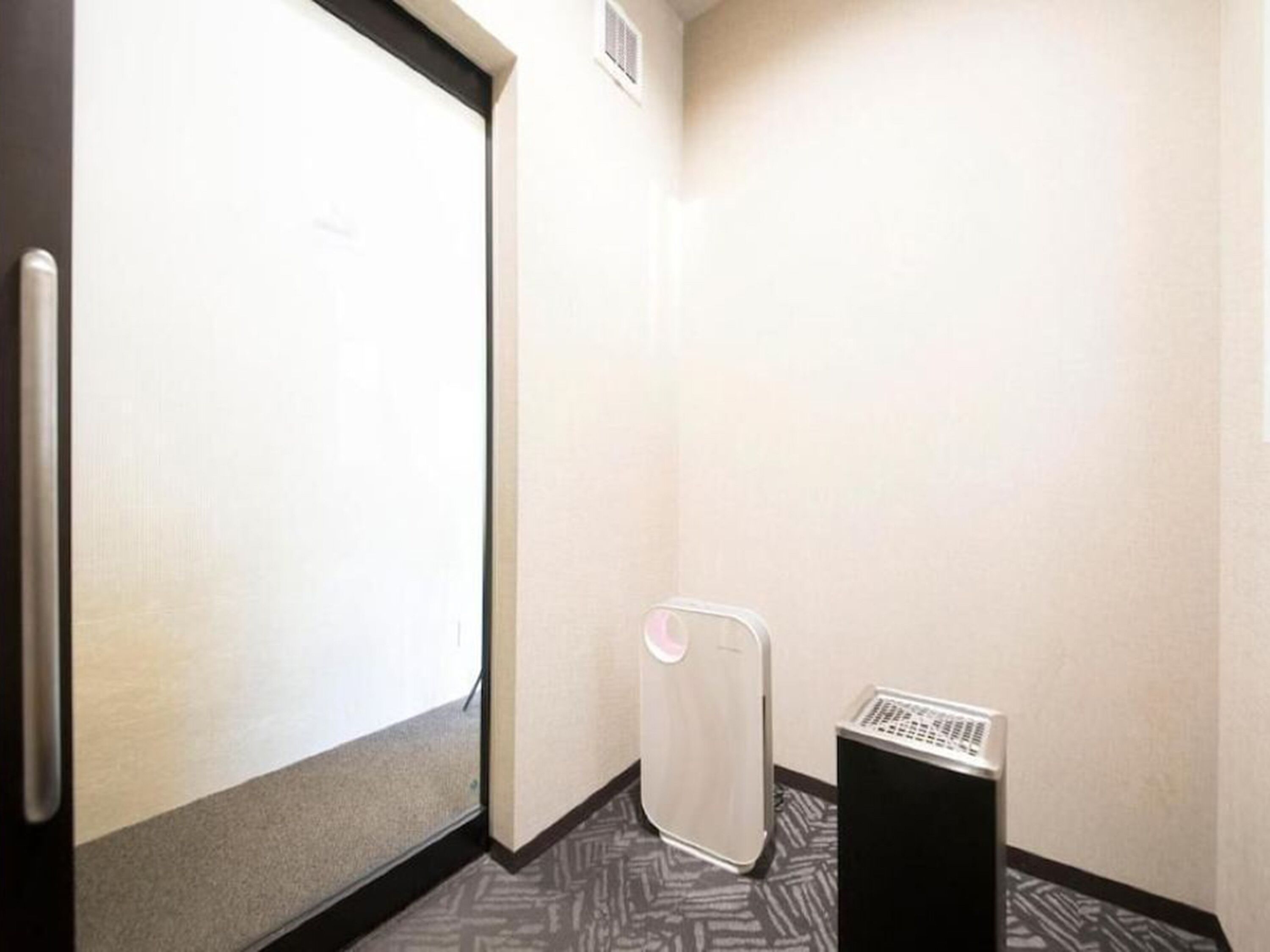 Una habitación de hotel con un ventanal grande, un radiador y una alfombra estampada.
