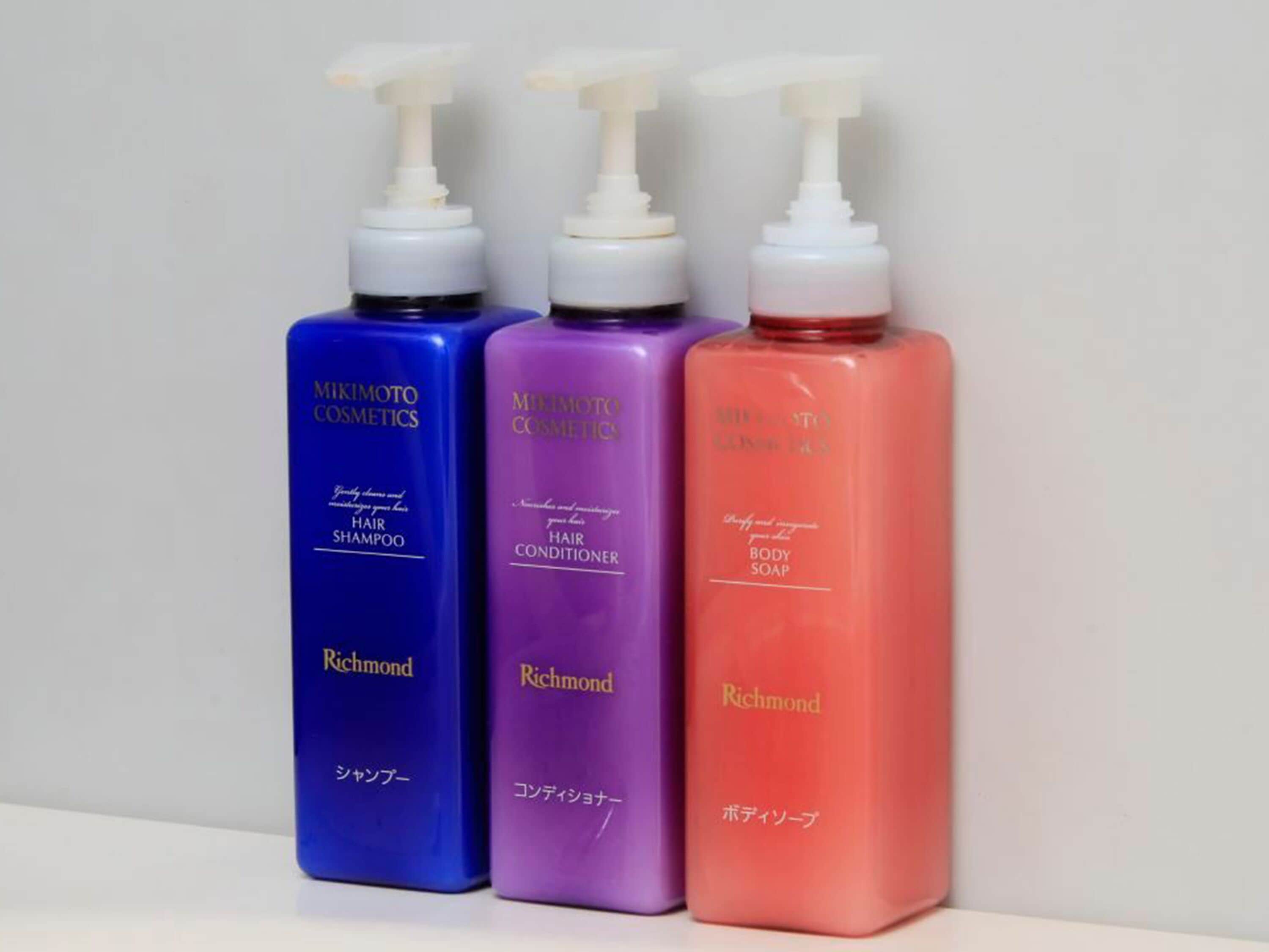 Three bottles of MIKIMOTO COSMETICS hair products in different colors.