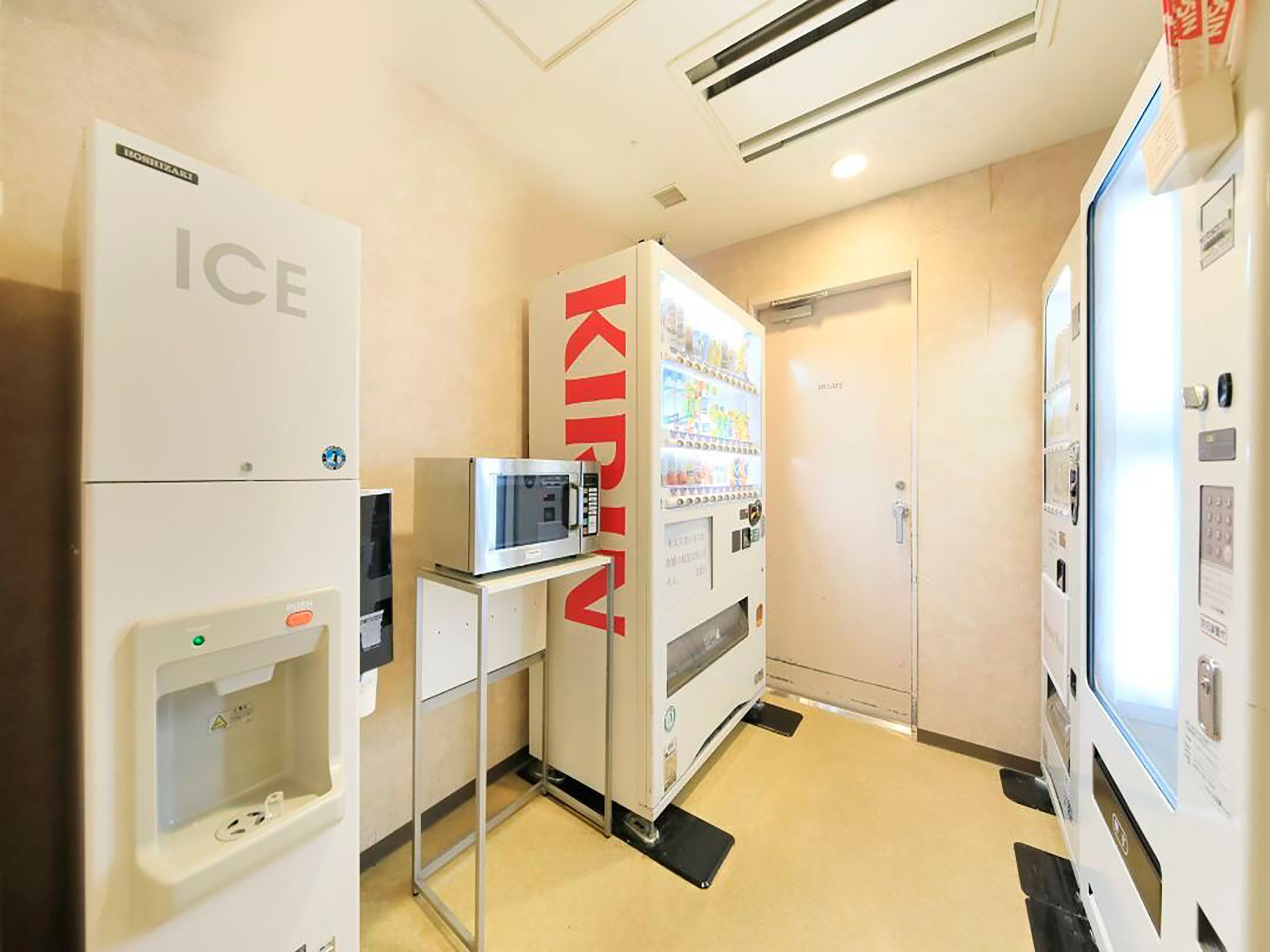 A hotel room with a minibar, a refrigerator, a microwave, and a vending machine.