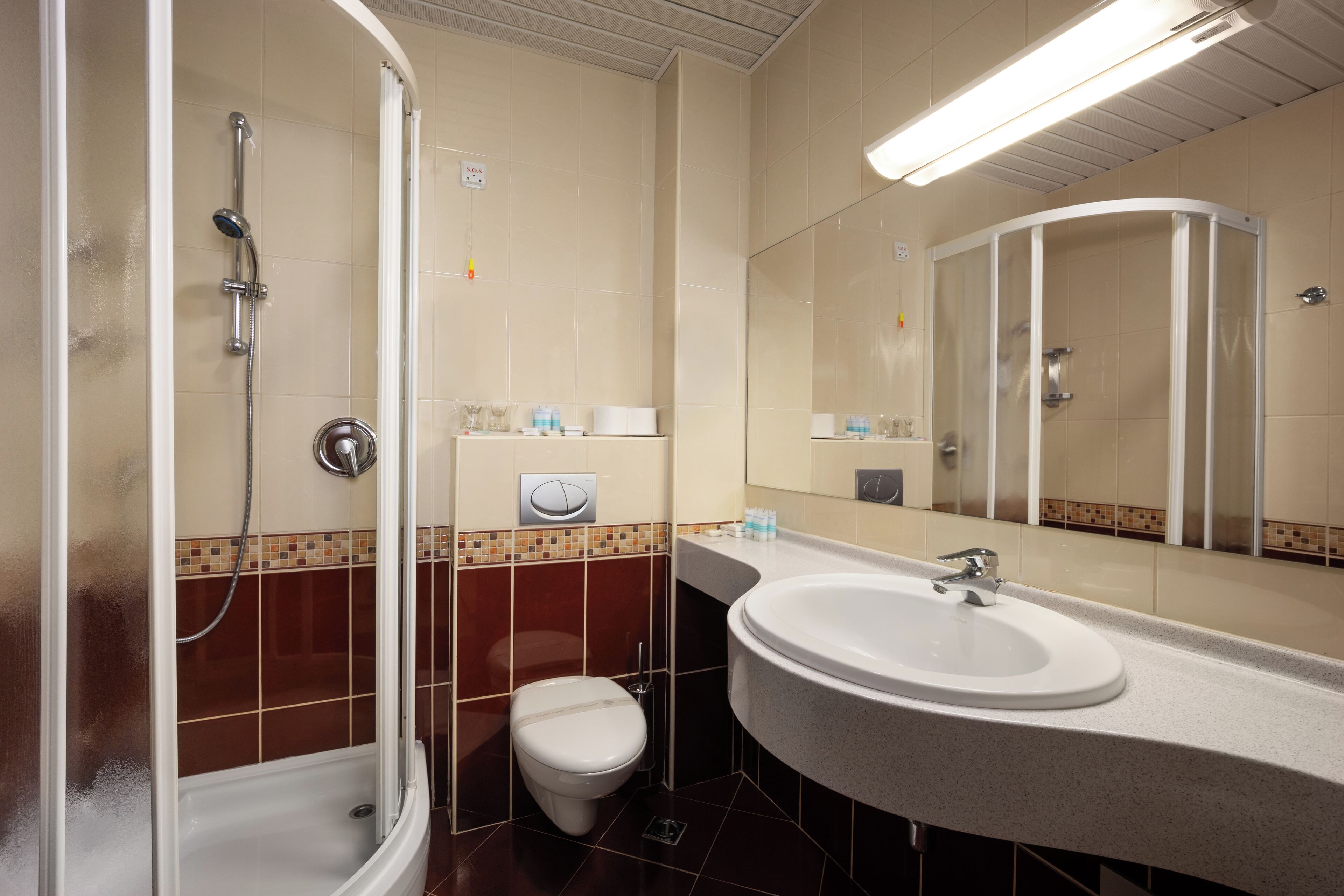 A bathroom with a shower, toilet, sink, and a mirror.